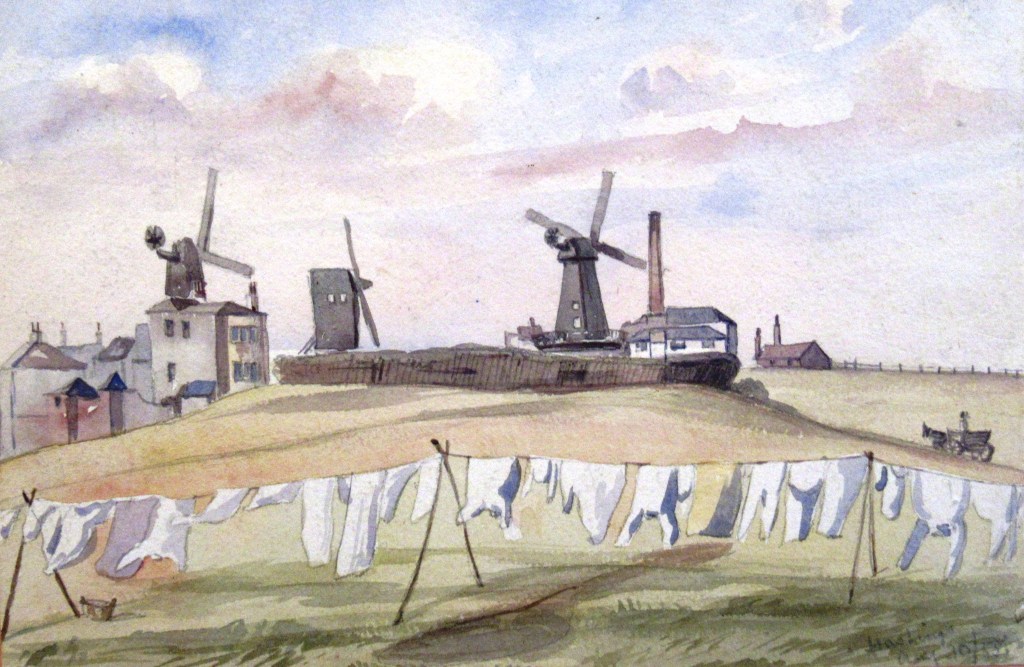 Watercolor painting depicting three windmills on a hill with a few buildings and laundry hanging in the foreground.